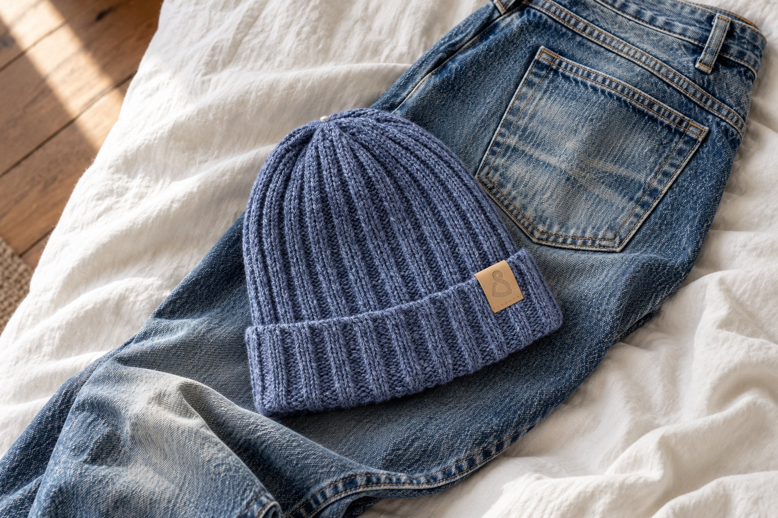 Cusco Jeans liegt auf einer getragenen Jeans – zwei vertraute Begleiter in sanftem Tageslicht.
